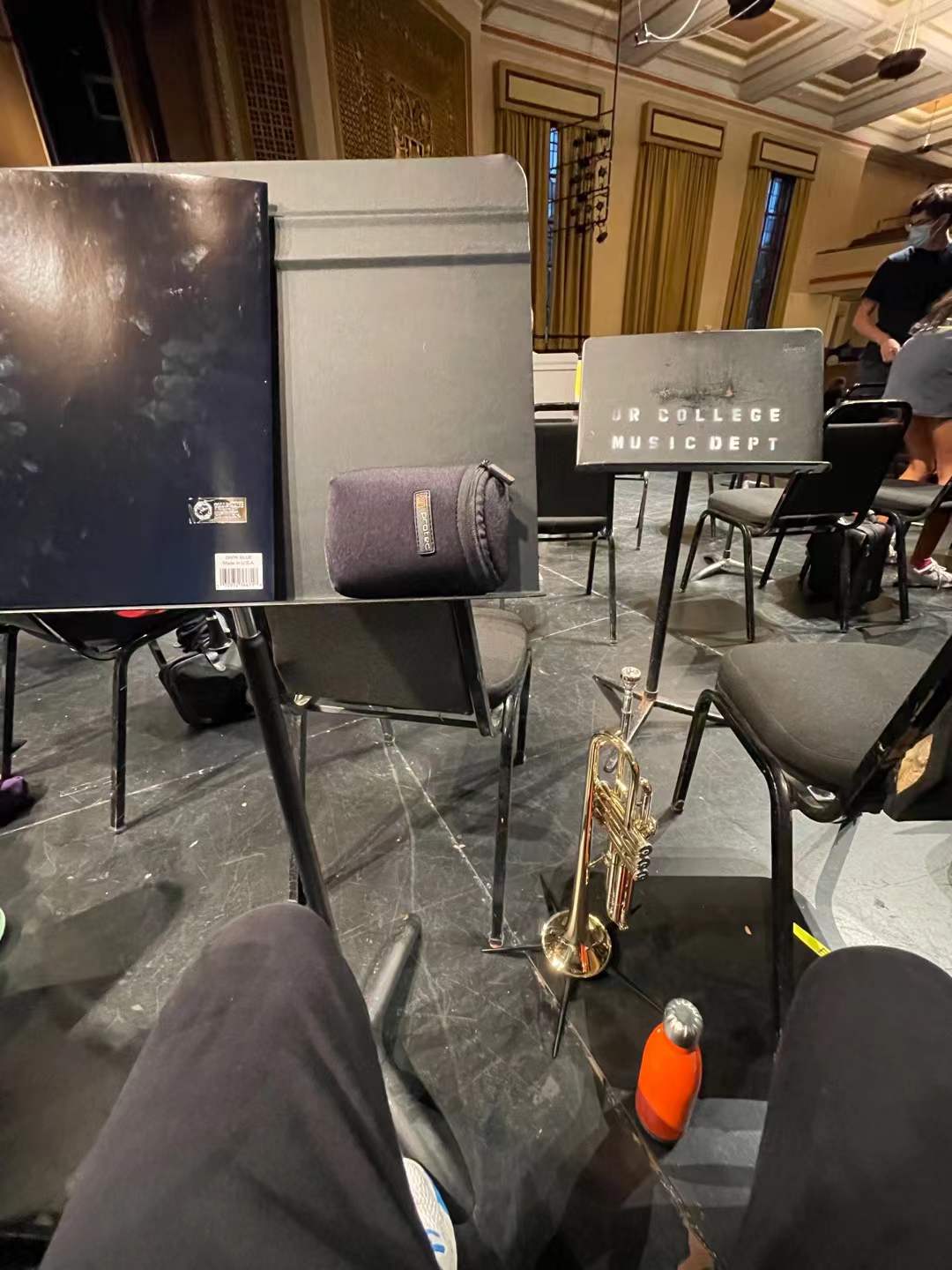 A trumpet beside music stands and chairs in a rehearsal hall